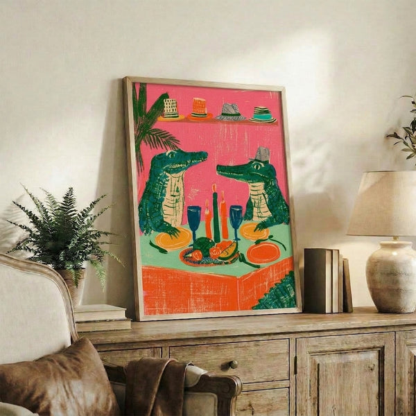 Quirky retro-style framed art print showing playful crocodiles in celebration attire dining together with wine and fruit, rendered in a bohemian folk aesthetic with bold hot pink and forest green hues.