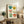 Cozy domestic kitchen wall art showing hand-painted pots filled with cheerful flowers in retro palette of teal, mustard, cream, and sage, framed as a poster.
