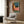 Contemplative nighttime interior with bedside telephone and open book, retro color scheme of teal green and warm orange, framed poster print on wall.