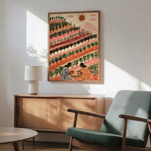 Framed retro boho poster of a sun-drenched hillside with two women, lush vegetation, and trees in soft terracotta, coral, and sage green hues creating a peaceful, warm aesthetic.