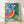 Retro boho still life poster featuring a sliced watermelon with vibrant coral red flesh and green rind, surrounded by colorful flowers and leaves in sage and forest green, set against a cobalt blue and cream background with decorative ceramic tile patterns.