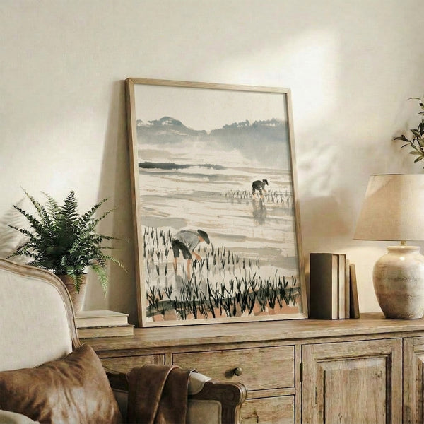 Framed watercolor print showing farmers tending rice paddies amid distant mountains, painted in soft taupe and sage with a melancholic, meditative atmosphere.