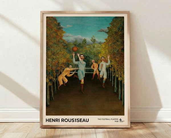 Framed art print of Henri Rousseau's The Football Players, a whimsical 1908 naive folk art painting depicting men playing football amid lush forest foliage in teal, ochre, and green tones.