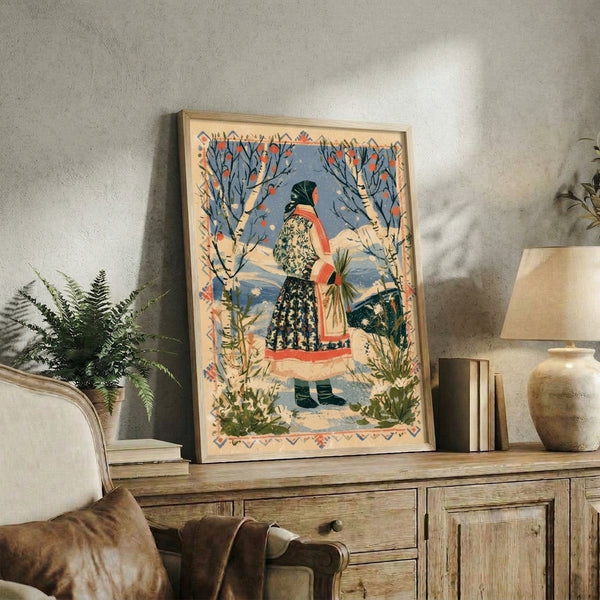 Cottagecore wall art print showing a woman in folkloric clothing among snow-dusted birch trees and red rowan berries, painted in a nostalgic vintage style with warm cream and cool blue palette.