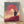Framed Japanese woodblock-style poster depicting a solitary samurai figure silhouetted against a glowing coral-red sunrise behind Mount Fuji, rendered in minimalist strokes with cream, navy, and dusty rose tones.