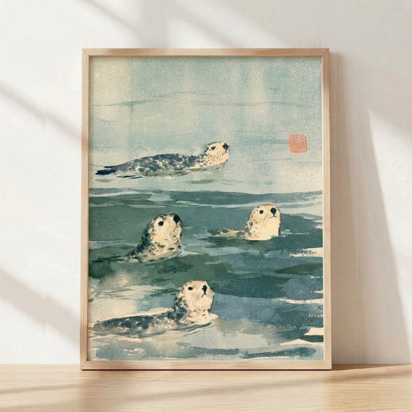 Framed Japanese woodblock-style watercolor print depicting seals swimming in teal and pale blue ocean waters with soft green undertones, rendered in a serene, naturalistic style.