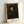 Minimalist portrait artwork showing a man's face in golden-brown palette with subtle shadowing, capturing a quiet, thoughtful presence in framed form.
