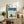 Japanese Showa era retro poster art in muted greens and creams showcasing a whimsical mountain skier at rest near a wooden bench, capturing quiet winter nostalgia.