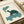 Tranquil framed artwork of a contemplative turtle exhaling pipe smoke among floating clouds, rendered in soothing teal and earthy tones with woodblock-inspired linework.