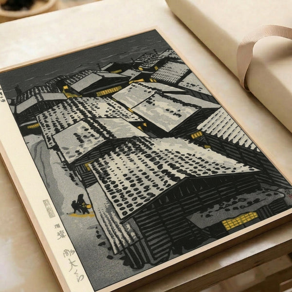 Vintage Japanese woodblock poster of a snow-covered village with stacked rooftops, lanterns glowing in muted gold, and a solitary figure amid charcoal blacks and soft greys, capturing winter's peaceful essence.