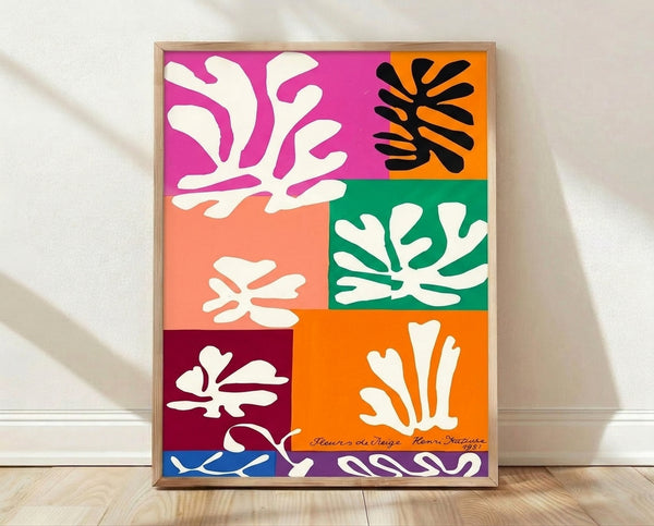 Abstract cut-out poster featuring organic flower shapes in soft pastels and muted tones, framed on a wall in a modern minimalist style.