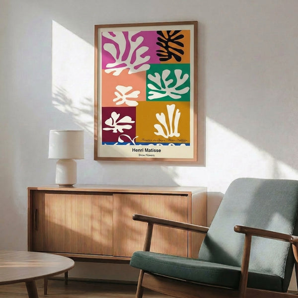 Framed minimalist floral artwork featuring bold primary colors and white organic shapes arranged in a cheerful, decorative composition inspired by cut-out techniques.