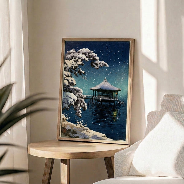 Vintage-style woodblock print of a snow-blanketed pavilion by water under stars, evoking calm winter solitude in teal and charcoal tones.