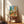 Vintage-style linocut artwork displaying desert-inspired objects including a potted cactus, acoustic guitar, wooden chair, and wide-brimmed hat against a cream background in warm retro colors.