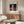Ghibli-style poster art with a young girl at the center of an enchanted bathhouse scene, blending pale cream and burnt orange with deep blacks for an atmospheric effect.