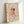 Studio Ghibli wall art featuring Chihiro and ethereal soot sprites in a surreal composition, executed in Japanese woodblock style with warm earth tones and mysterious deep red hues.