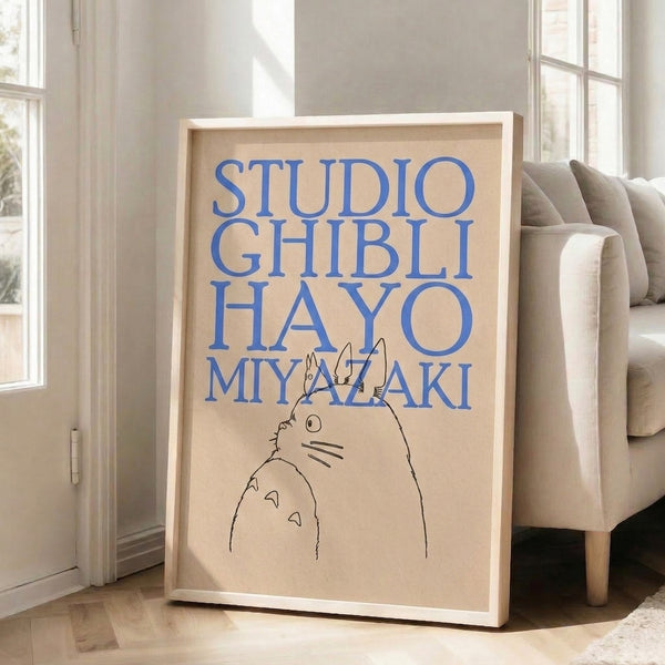 Minimalist cream-colored poster with black line art of Totoro and blue text, displayed framed as a Hayao Miyazaki homage.