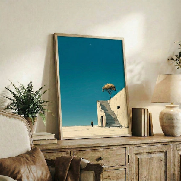 Surreal modern art print showing a solitary person climbing stairs in a dreamlike desert landscape under a glowing crescent moon in cream and charcoal tones.