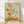 Surreal coquette poster art featuring jeweled mushrooms, daisies, and poppies in sage green, blush pink, and coral tones, framed on a wall with gold ornamental accents and dreamy whimsical mood.
