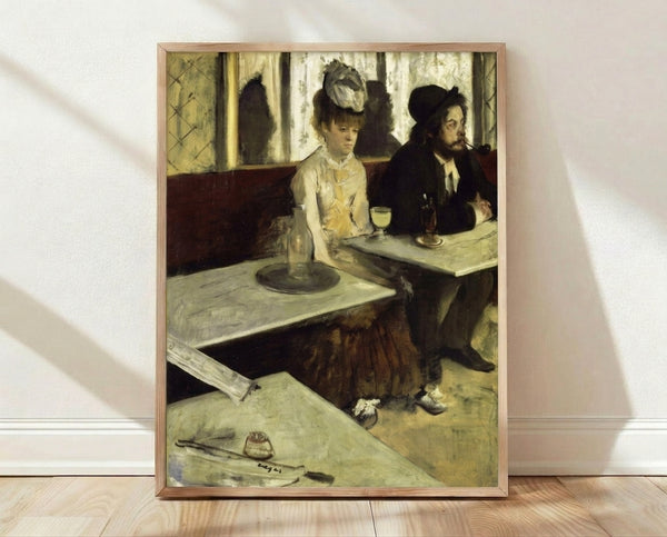 Framed vintage poster of a solitary figure in a hat seated at a table with an absinthe glass, rendered in muted greens and earth tones with a melancholic, introspective mood.
