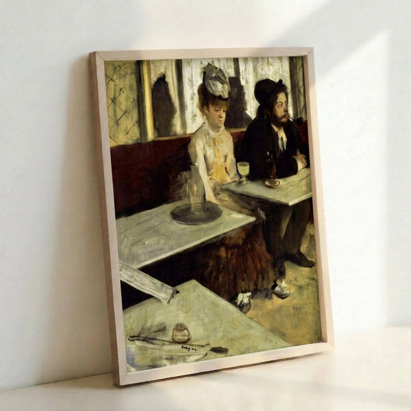 Framed poster showing a solitary person at a café table with absinthe, capturing a pensive moment through soft colors and impressionistic technique.