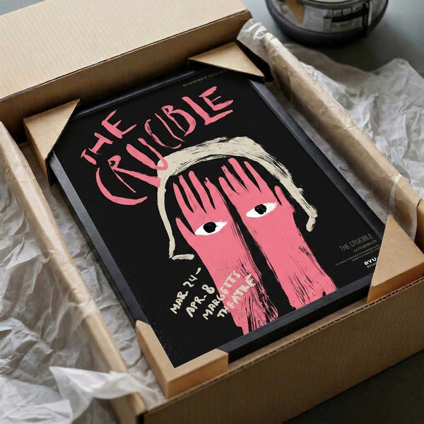 Dramatic pop art wall poster displaying a woman's haunting face with expressive eyes in vibrant hot pink and black against cream; modern artistic interpretation of The Crucible.