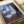 Wall-mounted poster of an enigmatic, introspective figure at a window overlooking a quiet city, executed in expressionist style with muted ochre and violet undertones.