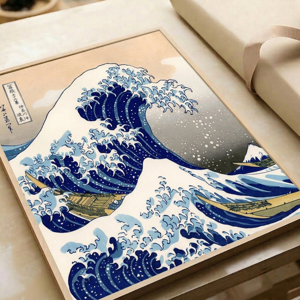 Dramatic ocean scene from a traditional Japanese woodblock print showing an enormous wave in prussian blue with cream and gold details, mounted as wall art.