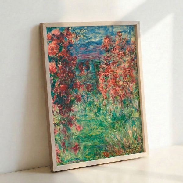 Monet's romantic garden scene The House In The Roses framed on a wall, rendered in soft impressionist style with abundant blooming flowers in warm rose and cream hues surrounding an intimate dwelling.