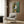 Modernist depiction of a figure with abstracted facial features in a subdued palette of warm and cool neutrals; matted poster art displayed on interior wall.