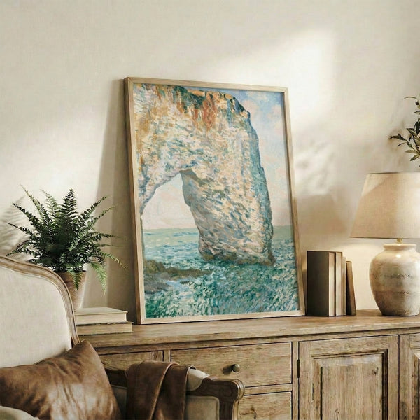 Monet's luminous portrayal of the Étretat arch formation with gentle waves and misty atmosphere in pale blue and ochre tones.