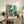 Modern art print of a simplified interior with turquoise window, ochre table, and black chair creating a peaceful, balanced composition.