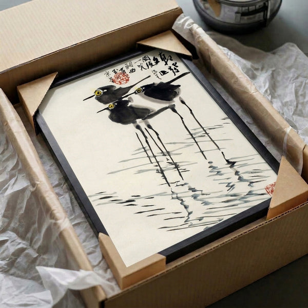 Serene woodblock-influenced print depicting birds with elongated legs wading through grass and water, composed in a restrained palette of black, gray, and cream.