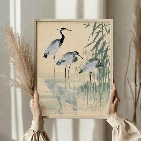 Framed art print depicting three birds standing in water among bamboo and reeds, rendered in an elegant Japanese style with a peaceful palette of pale blue, gray, and cream.