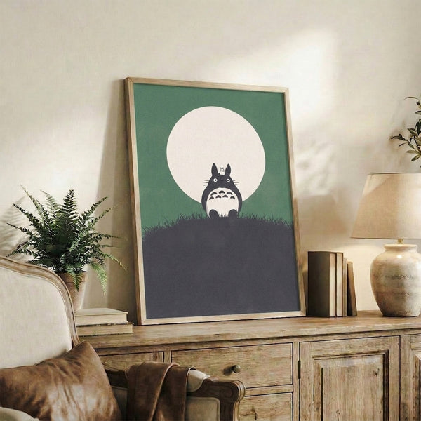 Peaceful Studio Ghibli poster art showing Totoro's shadowed form beneath a luminous moon, rendered in a modern style with soft sage green and dark gray palette.