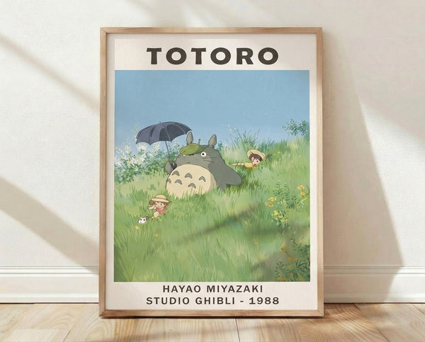 Whimsical Studio Ghibli poster featuring Totoro holding an umbrella in a lush meadow with children among tall grass and flowers in soft blue, green, and cream tones.