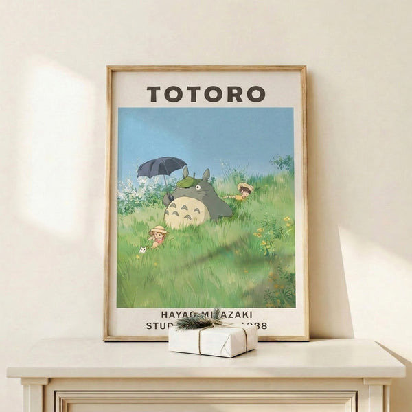 Peaceful Studio Ghibli wall art capturing a magical moment of Totoro in an umbrella-shaded meadow surrounded by children and wildflowers in muted pastels.
