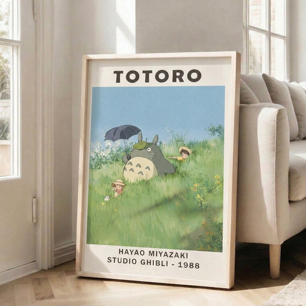 Charming framed print featuring the iconic gray forest spirit Totoro holding an umbrella while standing in a tranquil field of grass and flowers with cream and soft blue hues.