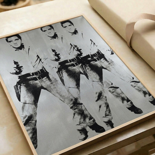 Andy Warhol's iconic triple Elvis composition framed on a wall, displaying the musician in western outfit repeated across bold, contrasting colors in classic pop art style.