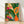Framed botanical linocut print featuring vibrant tropical fruits and flowers in forest green, coral orange, and magenta against a cream background, displayed on a wall.