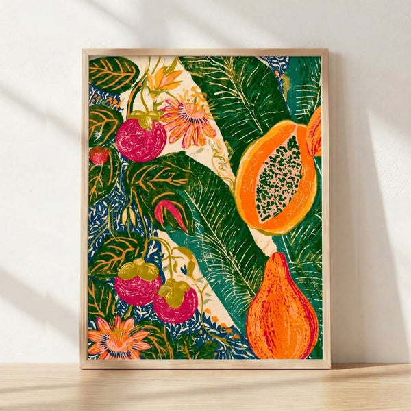 Framed botanical linocut print featuring vibrant tropical fruits and flowers in forest green, coral orange, and magenta against a cream background, displayed on a wall.