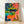 Whimsical boho folk art poster featuring a black panther among tropical plants and fruit baskets in coral pink, royal blue, and yellow-green tones.