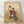 Framed Japanese woodblock print depicting two graceful geisha in ornate kimonos beside a glowing lantern amidst green grass, rendered in cream, black, red, and gold tones with serene elegance.