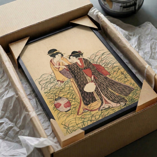 Framed poster showcasing two graceful geisha wearing intricate kimonos near a glowing lantern amidst foliage, executed in the refined ukiyo-e technique with cream, black, red, and gold tones.