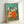 Contemplative ballet scene with dancers wearing striking red and yellow skirts, painted in impressionist style with cream and ochre highlights, mounted as wall decor.