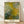 Impressionist painting of flowering bushes and trees in soft greens, whites, and ochre tones, framed poster hanging on a wall in a serene garden scene.