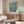 Serene impressionist poster featuring blooming almond branches in cream and white flowers against a peaceful teal backdrop with touches of olive and golden detail.