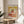 Museum-quality art print depicting a vaulted hallway receding into shadow, pale golden and gray palette creating an introspective, quietly unnerving environment.