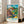 Impressionist art print of a peaceful rural cottage landscape with dynamic sky, trees, and fields executed in vibrant brushwork using cream, turquoise, green, and golden yellow palette.
