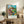Serene pastoral landscape poster featuring a village house among fields and trees in impressionist style with swirling brushstrokes and calming turquoise, sage green, and rust-gold colors.